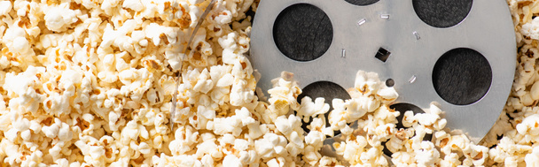 top view of film bobbin on airy delicious popcorn, banner, cinema concept - Photo, Image