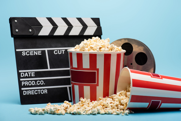 clapperboard, bobina di film e secchi con popcorn su blu, concetto di cinema - Foto, immagini