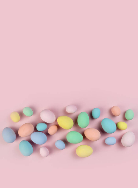 Πολύχρωμα πασχαλινά αυγά και φτερά σε παστέλ χρώματα βρίσκονται σε ροζ φόντο. Εορταστική κάρτα Πάσχα. - Φωτογραφία, εικόνα