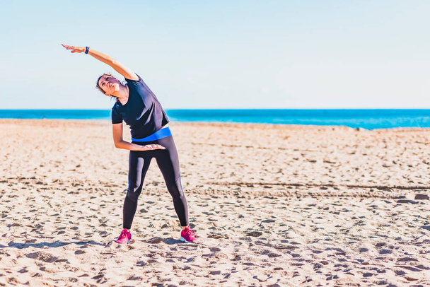 Donna di mezza età che fa esercizio sulla spiaggia - Foto, immagini