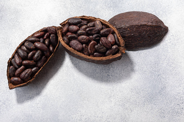 Разделенная капсула какао с какао-бобами на светло-сером фоне, вид сверху, пространство для копирования - Фото, изображение