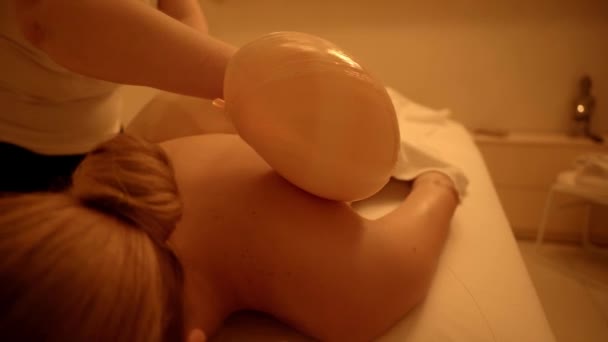 masseur massaging client with sea shell in spa salon  - Πλάνα, βίντεο