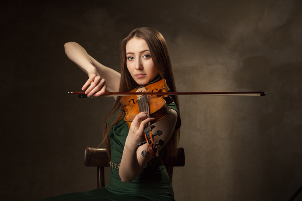 Beautiful young woman playing violin over black - Fotografie, Obrázek