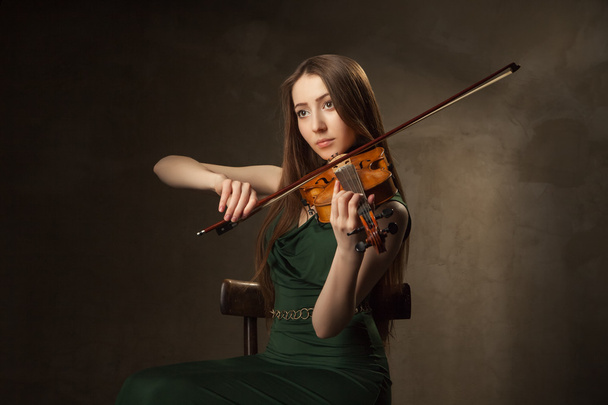 Beautiful young woman playing violin over black - Valokuva, kuva