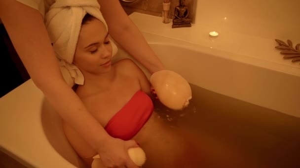 terapeuta masszírozás fiatal ügyfél tengeri kagyló fürdőkádban vízzel - Felvétel, videó