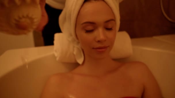 esthéticienne versant l'eau des coquillages sur la femme dans la baignoire avec de l'eau - Séquence, vidéo