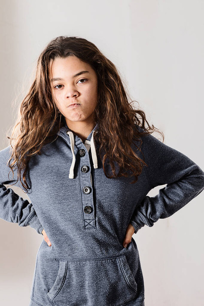 Teen is angry and wearing a blue sweatshirt while posing - 写真・画像