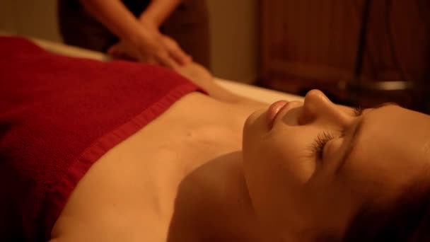 young woman with closed eyes receiving massage in spa salon - Filmati, video