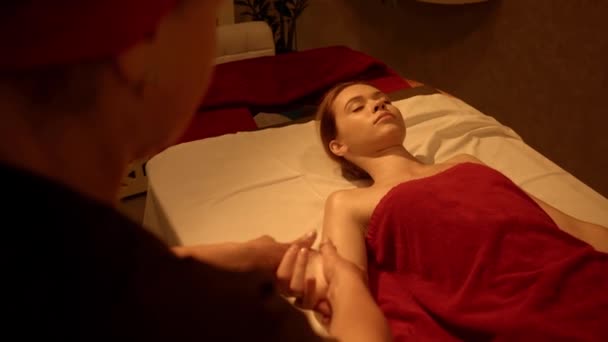 женщина с закрытыми глазами получает массаж рук от массажиста в спа-салоне - Кадры, видео