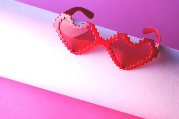 Ροζ γυαλιά σε σχήμα καρδιάς σε ροζ φόντο. Ημέρα του Αγίου Βαλεντίνου. - Φωτογραφία, εικόνα