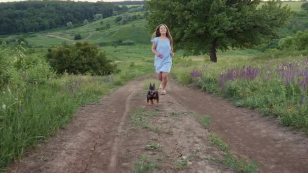 Χαμογελαστή έφηβη που βγάζει βόλτα το σκύλο της με λουρί στη φύση. - Πλάνα, βίντεο
