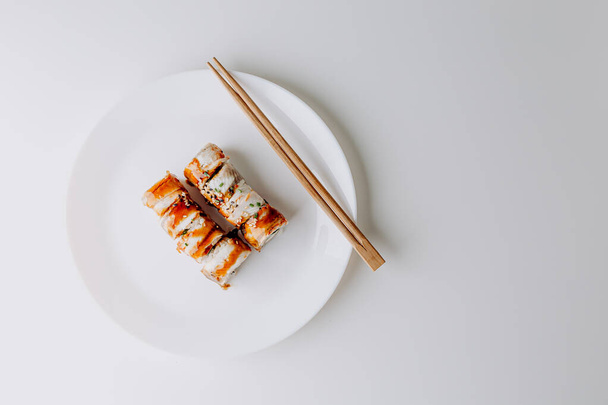 Comida japonesa: set de sushi maki y nigiri. Rollos de sushi (Filadelfia) con arroz, salmón de pescado, anguila ahumada, aguacate, queso crema, salsa de soja Teriyaki, sésamo. Palillos, wasabi y jengibre en escabeche. - Foto, imagen