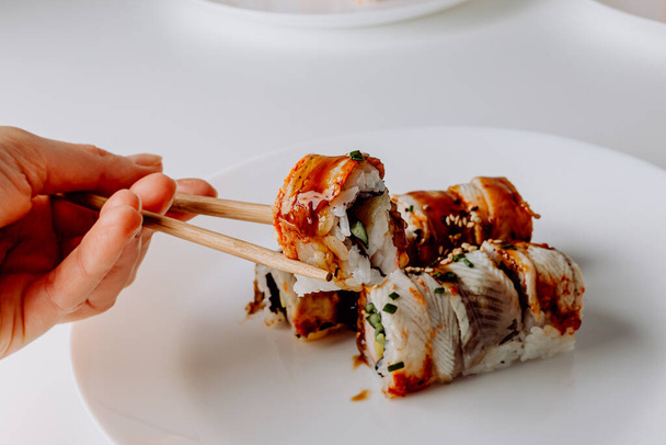Japanese food: maki and nigiri sushi set. Sushi rolls (Philadelphia) with rice, fish salmon, smoked eel, avocado, cream cheese, soy Teriyaki sauce, sesame. Chopsticks, wasabi and Pickled Ginger. - Fotografie, Obrázek