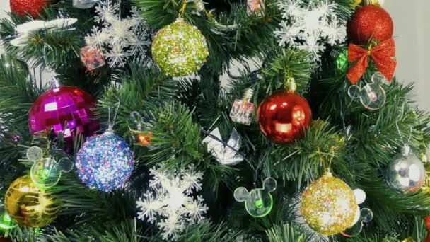 Fényes háttérrel villogó izzók és színes dekorációk egy karácsonyfán - Felvétel, videó