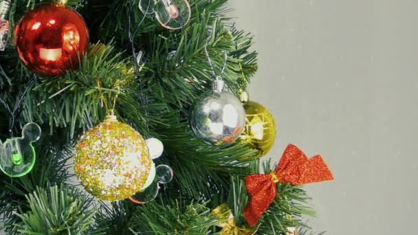 Σε ένα φωτεινό φόντο, αναβοσβήνει φώτα και πολύχρωμα παιχνίδια σε ένα πράσινο χριστουγεννιάτικο δέντρο - Πλάνα, βίντεο