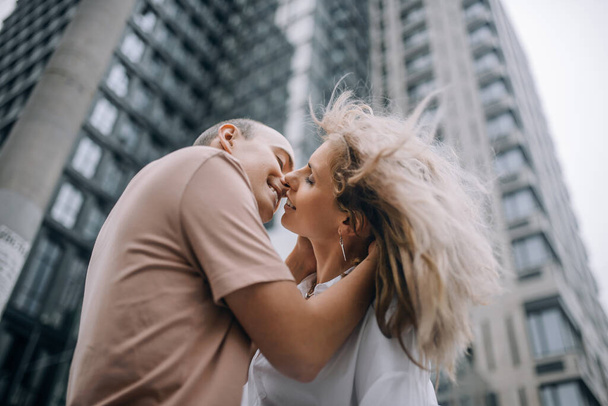 Gyönyörű szerelmespár csókolózik egy felhőkarcoló hátterében. Szerelem a nagyvárosban - Fotó, kép