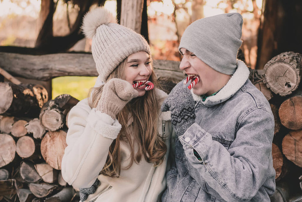 Пара, сидящая на фоне дров, поедающая конфеты и улыбающаяся друг другу - Фото, изображение