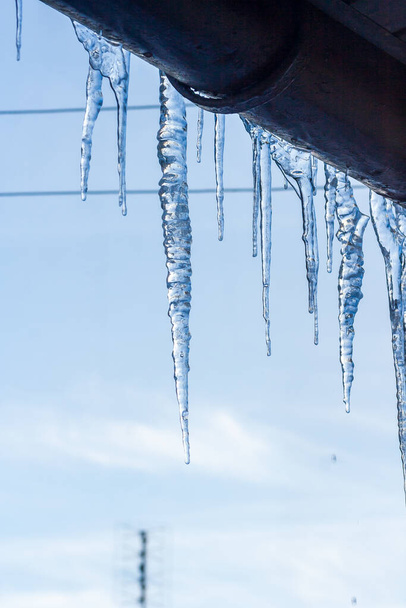 Eiszapfen hängen vom Hausdach. Winterkonzept. Nahaufnahme Gefahr Eiszapfen. Eingefrorenes Klima. Frostwinter - Foto, Bild