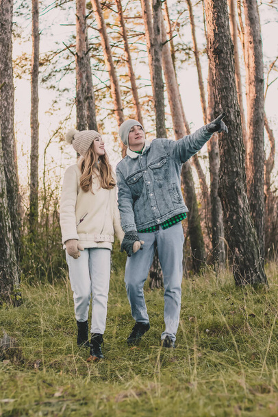 Facet trzyma dziewczynę za rękę i spaceruje po lesie sosnowym. - Zdjęcie, obraz