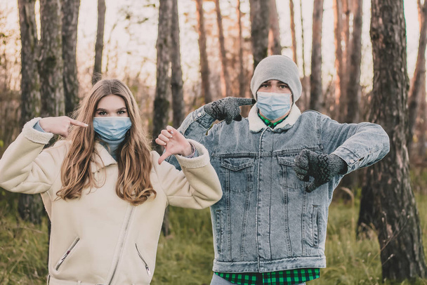 Парень и девушка в медицинских масках в сосновом лесу - Фото, изображение