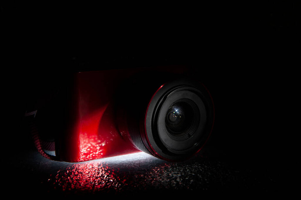 Objectif caméra rouge avec éclairage du fond sur base texturée - Photo, image