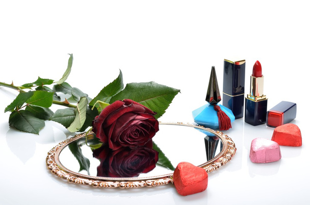 Perfumy, szminka, lustro serca cukierków i czerwona róża w martwej - Zdjęcie, obraz