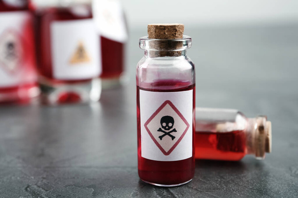 Glass vials of poison with warning sign on grey stone table, closeup - Photo, Image