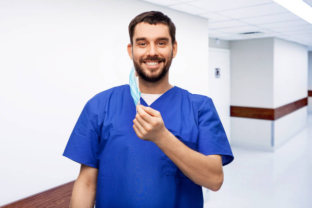 smiling male doctor in blue uniform with mask - Zdjęcie, obraz