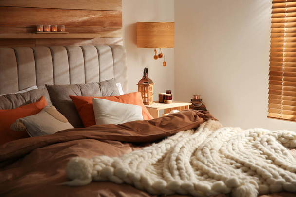 Acogedor dormitorio interior con manta de punto y cojines - Foto, imagen