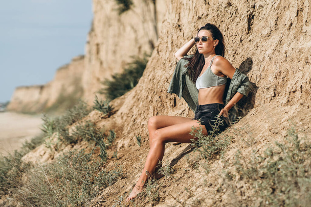 Brunette girl in hat relaxing on the beach with rocks on background - Valokuva, kuva