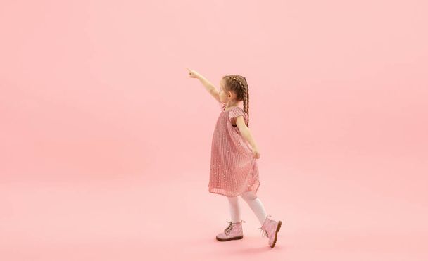 Childhood and dream about big and famous future. Pretty longhair girl isolated on coral pink background - Foto, immagini