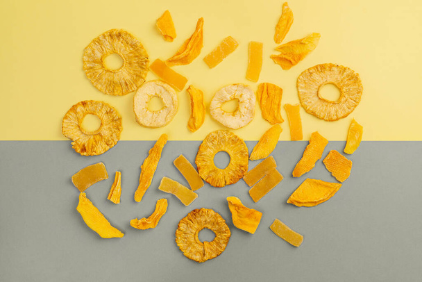 Variedad de fruta seca sobre fondo amarillo y gris, vista superior, orientación horizontal - Foto, Imagen