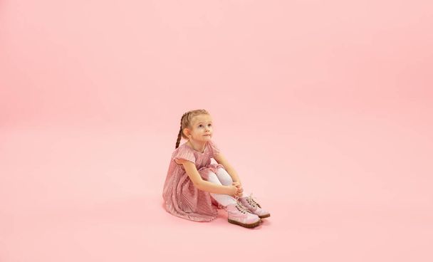 Childhood and dream about big and famous future. Pretty longhair girl isolated on coral pink background - Photo, image