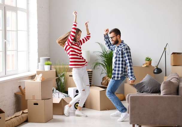 Full body side view of delighted young couple man and woman jumping happily while having fun during moving into new apartment - Foto, afbeelding