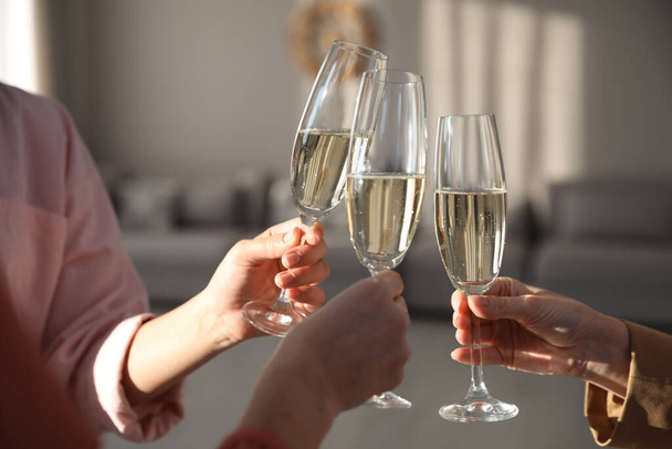 People clinking glasses of champagne in living room, closeup. Holiday cheer and drink - Valokuva, kuva