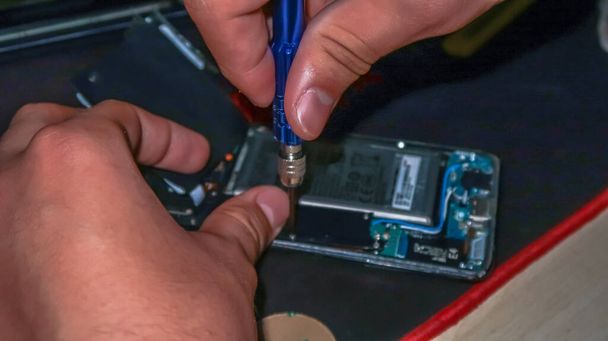 Крупним планом руки ремонтують смартфон з інструментами на столі
 - Фото, зображення