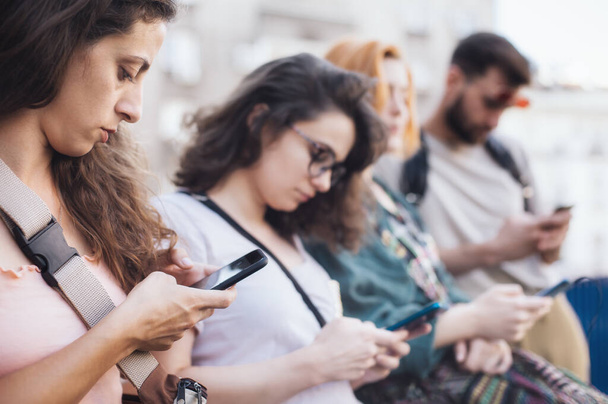 Group of friends using smartphones together. Young people addiction to new technology trends. Youth, new generation internet friendship concept. Emotional isolation and depresion - Foto, Bild