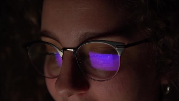 4K, kobieta w okularach przeglądająca się z komputerem późno w nocy. Ekran odbija się w jej okularach. Osoba pracująca w nocy. - Materiał filmowy, wideo