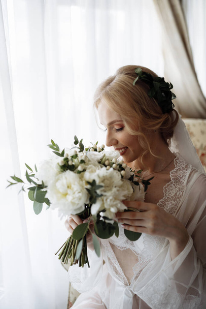 Wedding preparation. Beautiful young bride in white wedding dress indoors. High quality photo - Fotó, kép