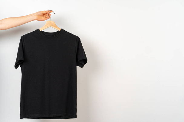 Black plain t-shirt hanging on a hanger - Fotó, kép