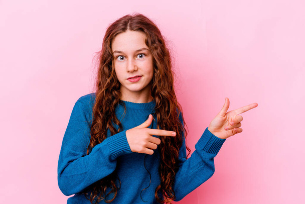 Little caucasian girl isolated on pink background shocked pointing with index fingers to a copy space. - Zdjęcie, obraz