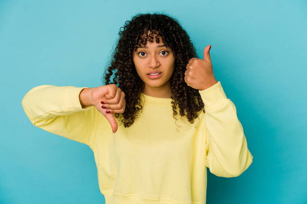 Young african american afro woman isolated showing thumbs up and thumbs down, difficult choose concept - Photo, Image