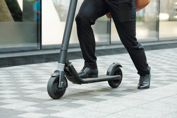 Close-up image of man riding electric scooter when hurrying to work in the morning - Photo, Image