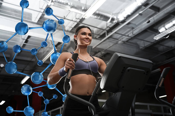 Metabolism concept. Molecular chain illustration and young woman working out on elliptical trainer in modern gym - Valokuva, kuva