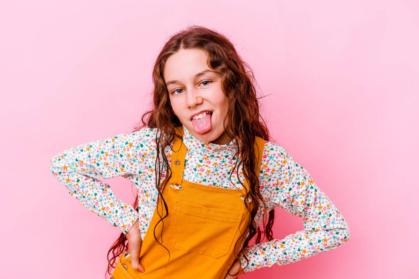 Little caucasian girl isolated on pink background funny and friendly sticking out tongue. - Photo, Image