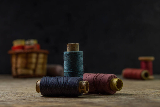 Старые катушки цветной нитки на деревянной поверхности. Цветная нить для шитья. - Фото, изображение
