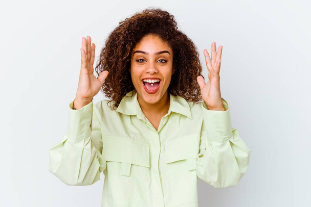 Jeune femme afro-américaine isolée sur fond blanc recevant une agréable surprise, excitée et levant la main. - Photo, image