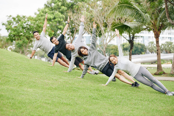 Groep van positieve fit jonge Aziatische mensen staan in zijbalk op helling op universitaire campus - Foto, afbeelding