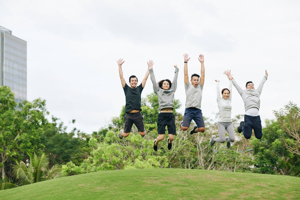 Podekscytowani młodzi Wietnamczycy skaczący po treningu na świeżym powietrzu w parku miejskim - Zdjęcie, obraz