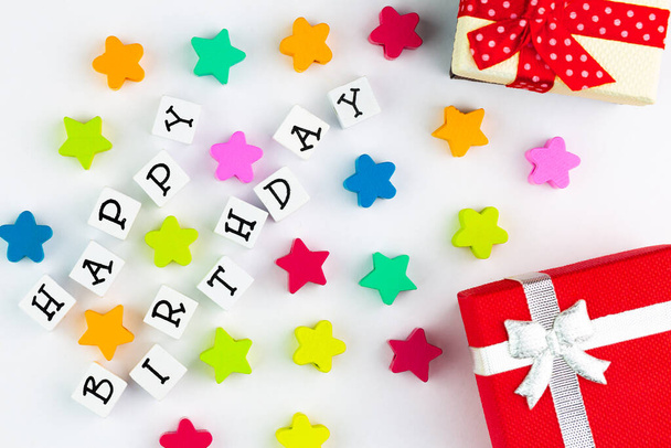 Текст "С днем рождения" организован из блоков на белом фоне, рядом с красочными звездами и подарочными коробками - Фото, изображение